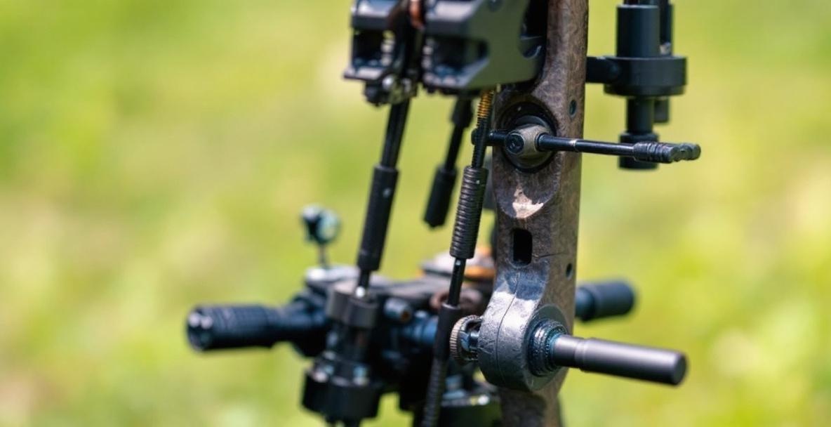 Close-up of bow sight pins with a blurred grassy background.